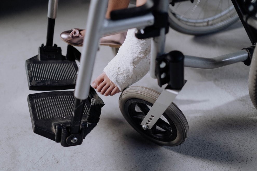 persona en silla de ruedas con pie escayolado