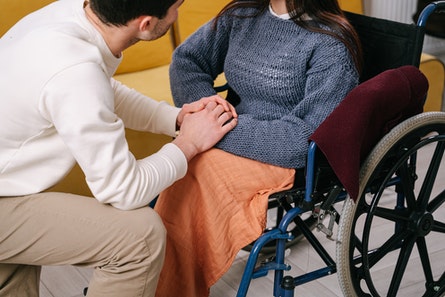 hombre da la mano a mujer en silla de ruedas