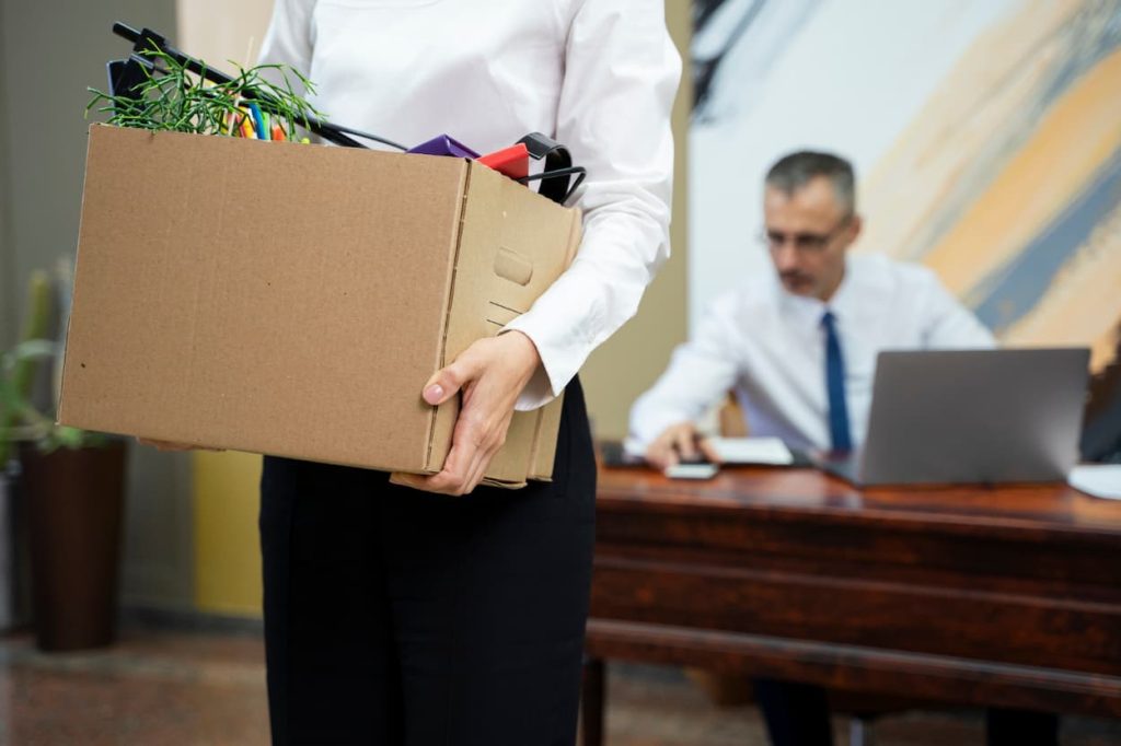 mujer cargando caja mientras sale de oficina