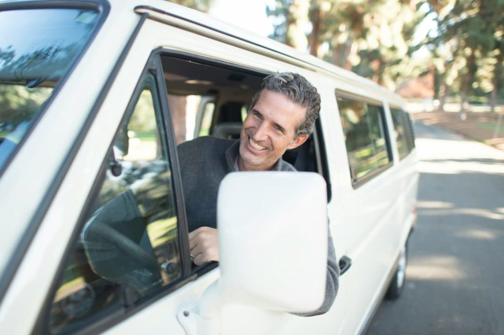 hombre sonriente conduciendo mini van